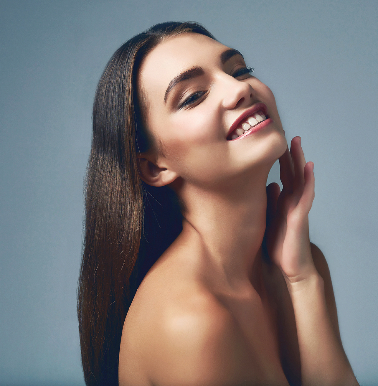 brunette model smiling and touching her face