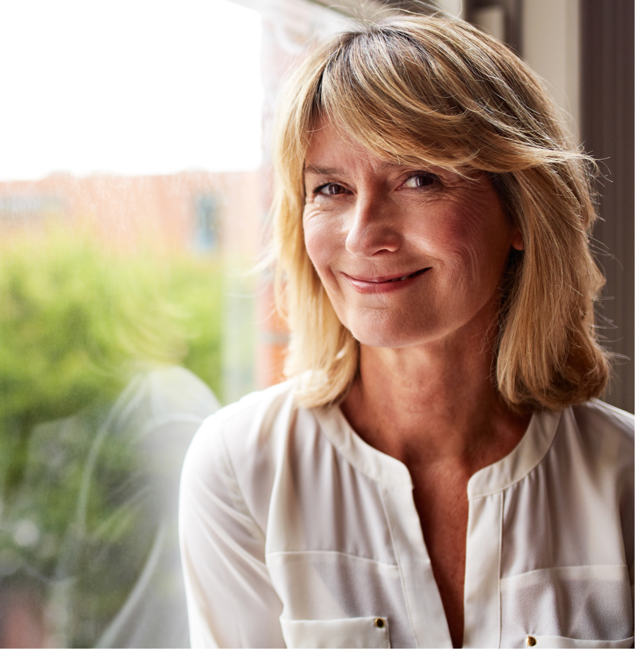 middle aged woman smiling by a window